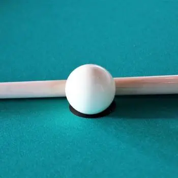 cue ball next to a pool cue on a pool table